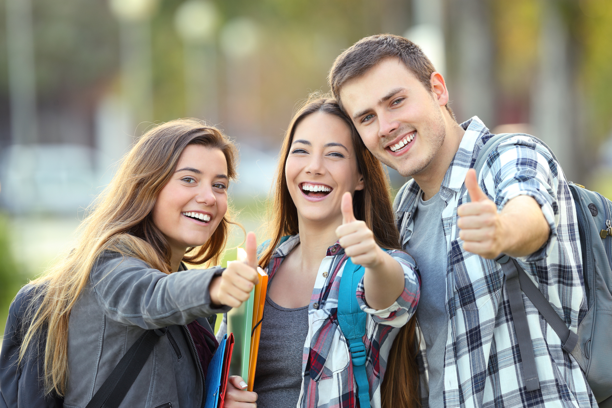 three happy students with thumbs up
